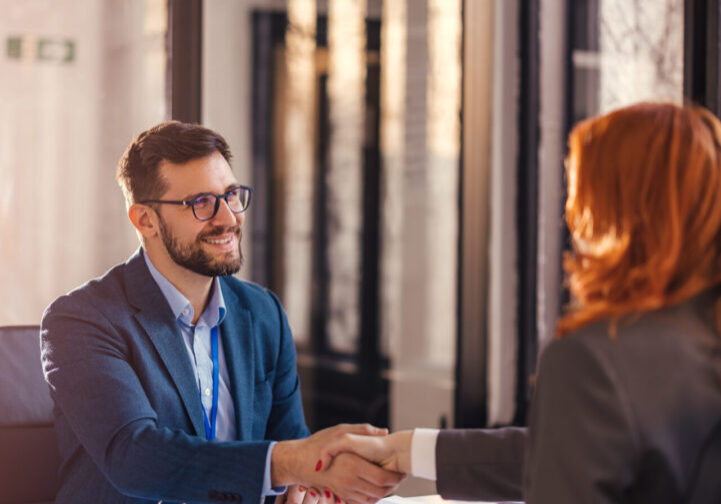 Happy bank manager shaking hands with a client after successful agreement in the office.