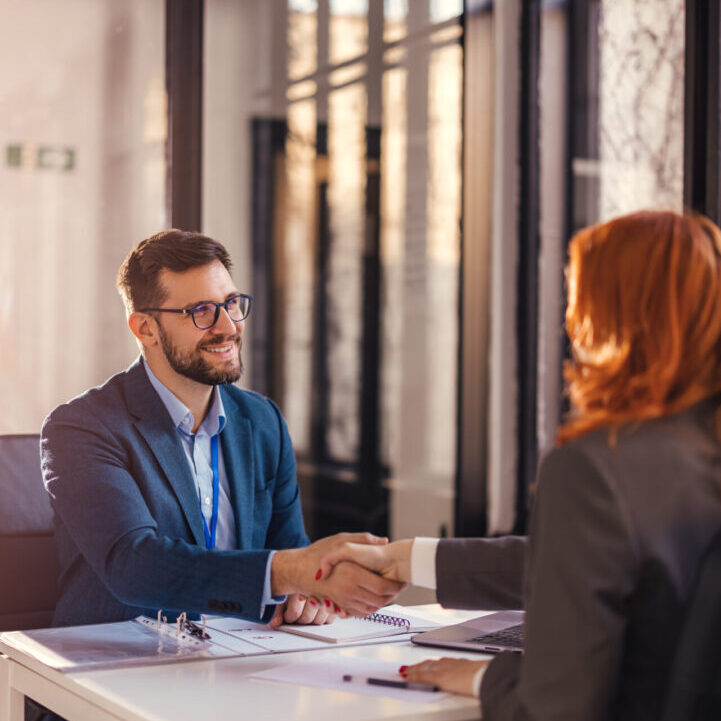 Happy bank manager shaking hands with a client after successful agreement in the office.